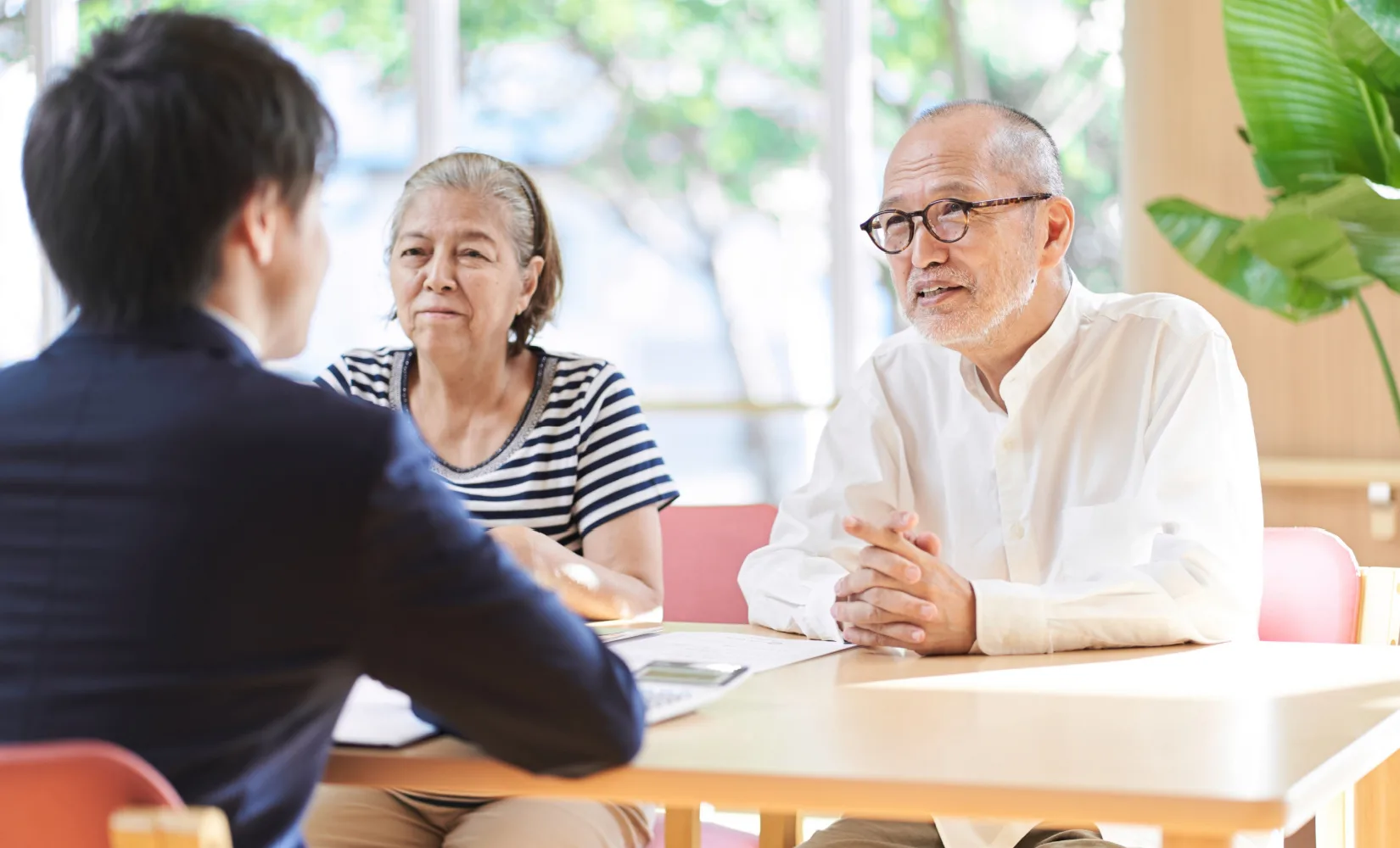 An older couple sits across a table from a younger man.