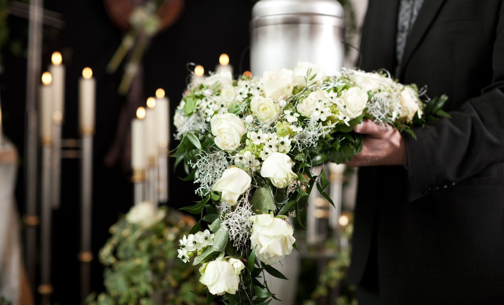 A man holding funeral flowers.