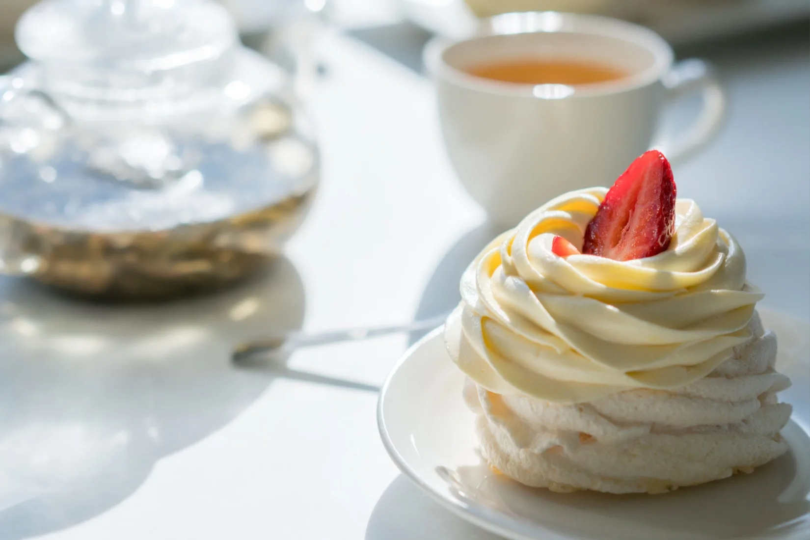 A cream cake on a table with a cup of tea.