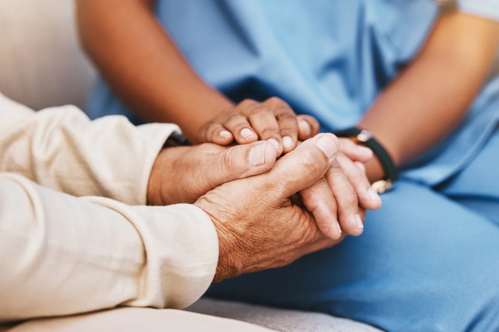 An elderly person holding hands with a nurse.