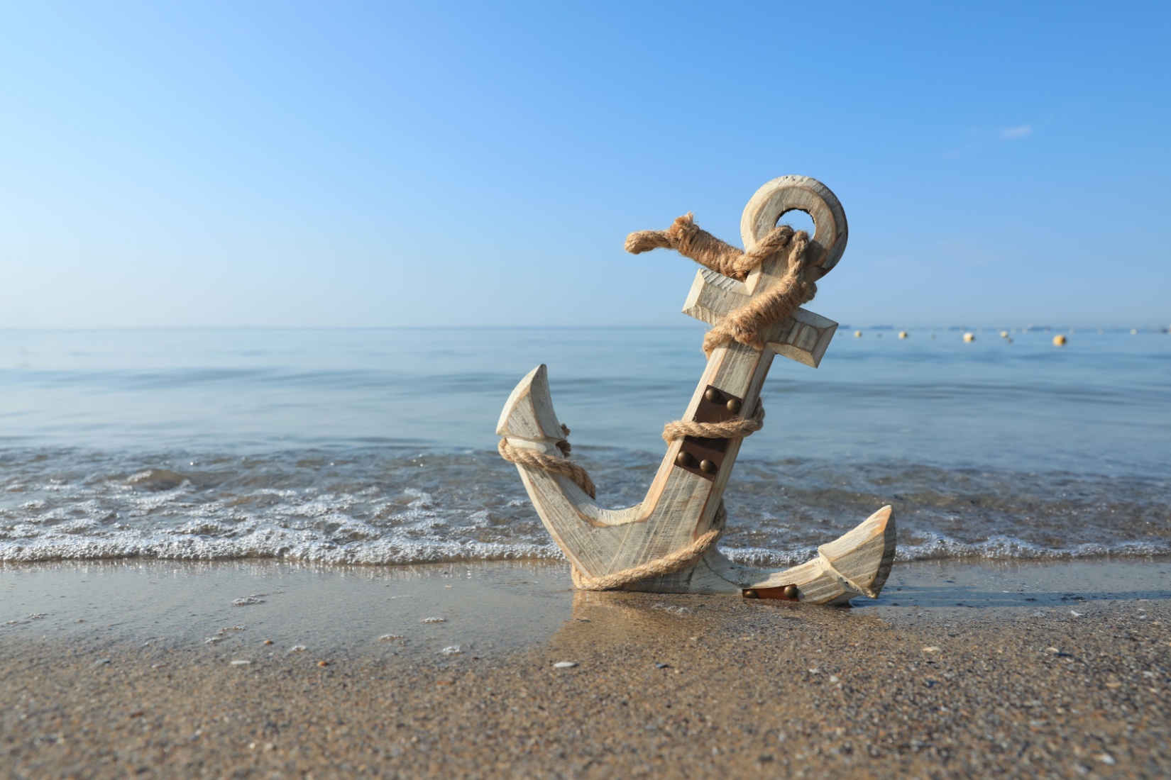 A wooden anchor on a beach.