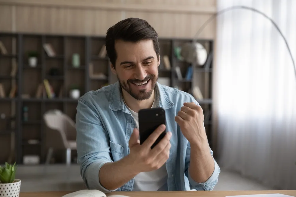 A man smiling at a message on his phone.