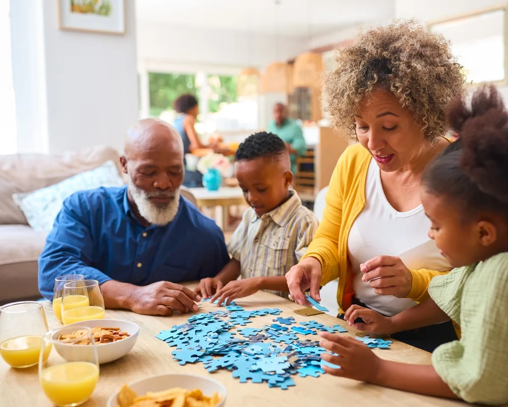 Grandparents doing a jigsaw with their two grandchildren.