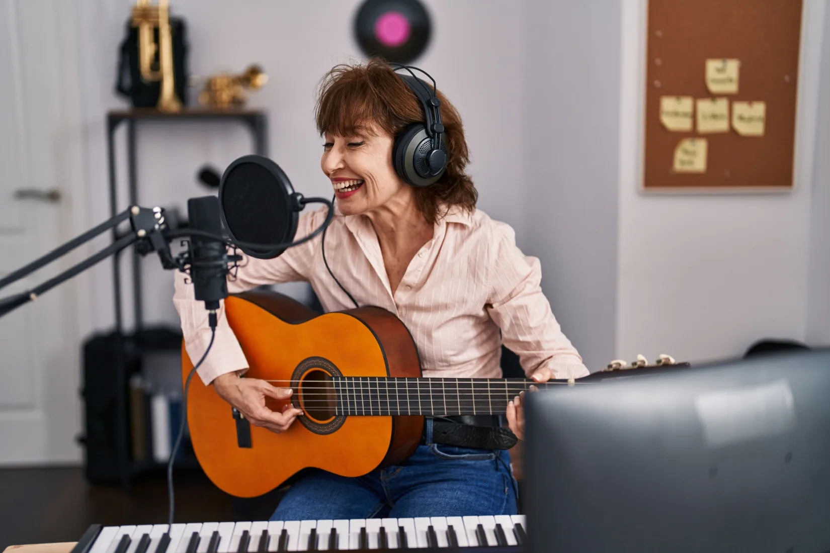 A woman playing a guitar in a music studio.