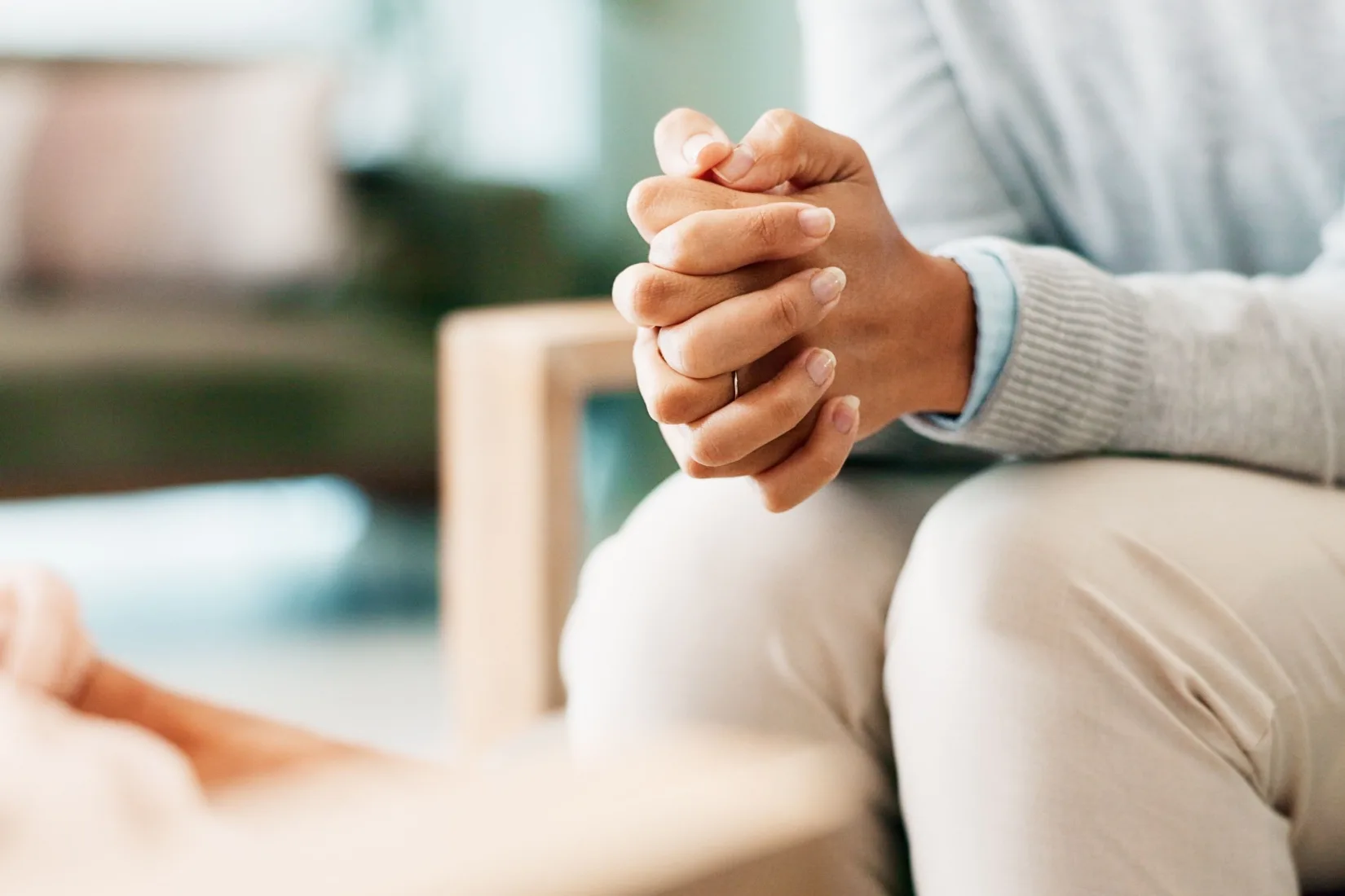 A woman sitting with her hands clasped.
