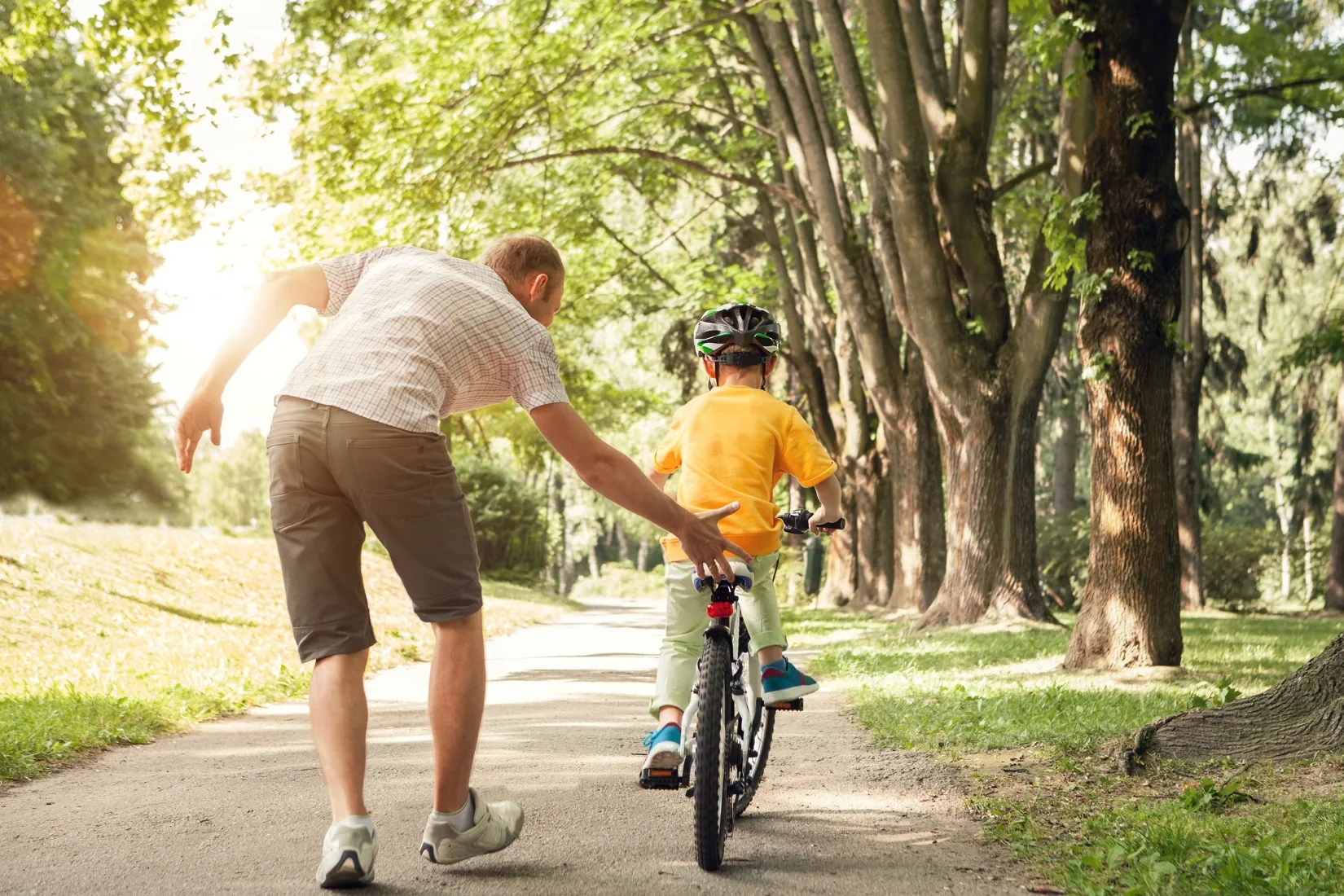 A father teaching a child to ride a bike.
