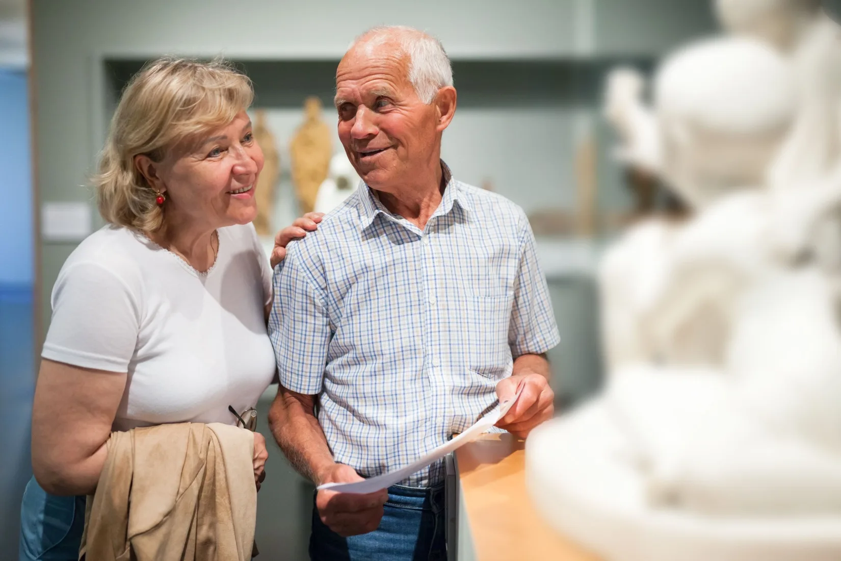 A couple looking at a statue in a museum.