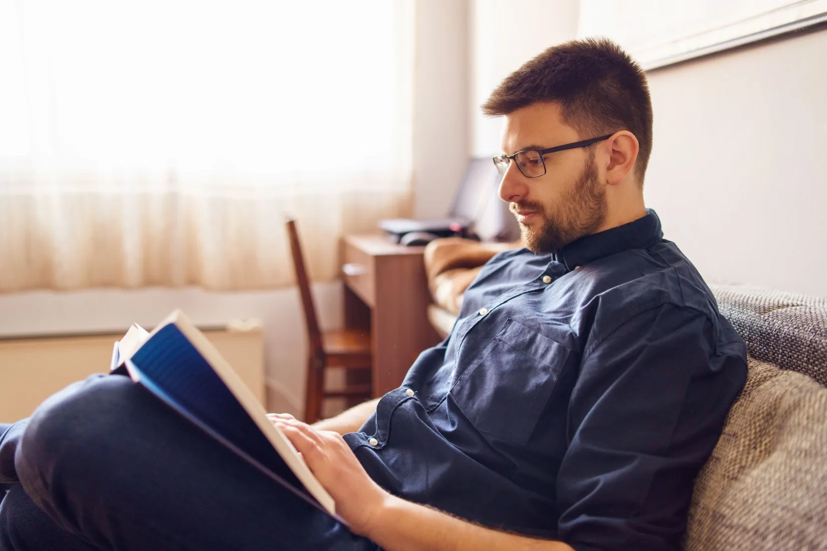 A man reading a book in his home.