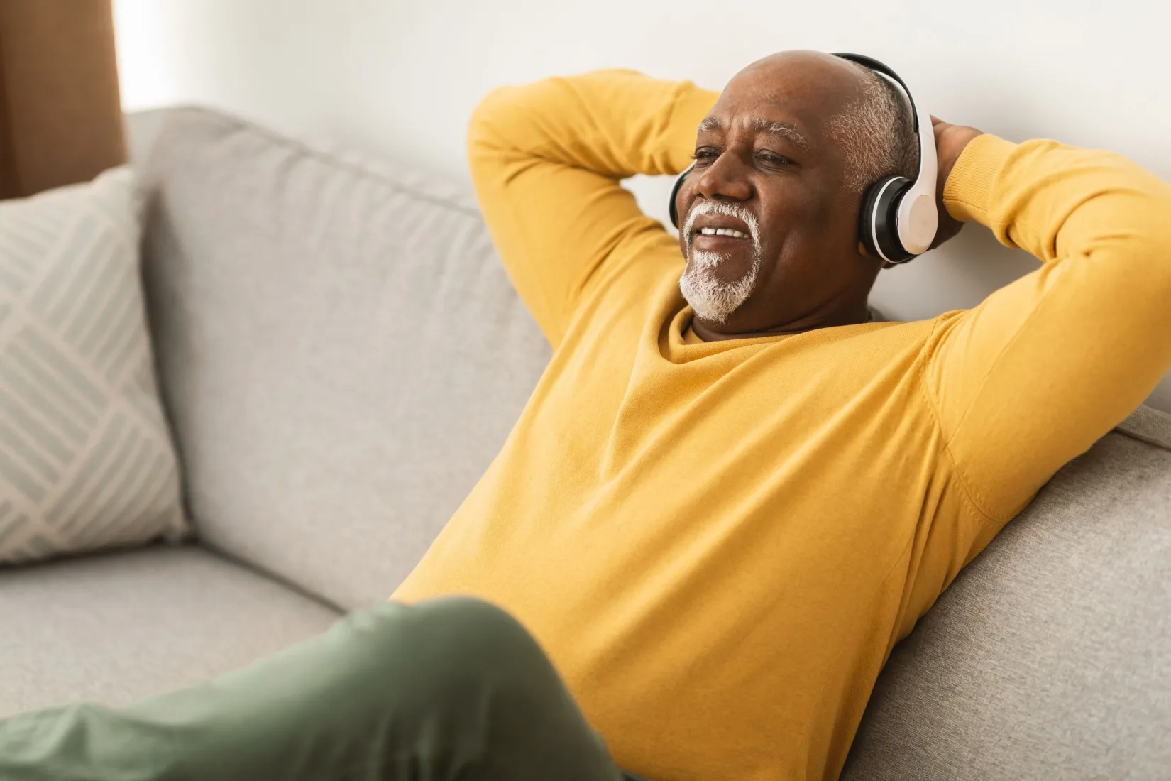 A man relaxing on a sofa with his hands behind his head.