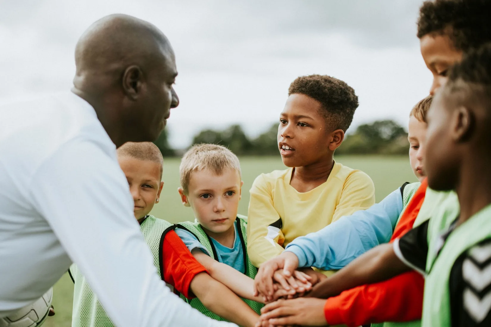 A man coaching a junior football team.