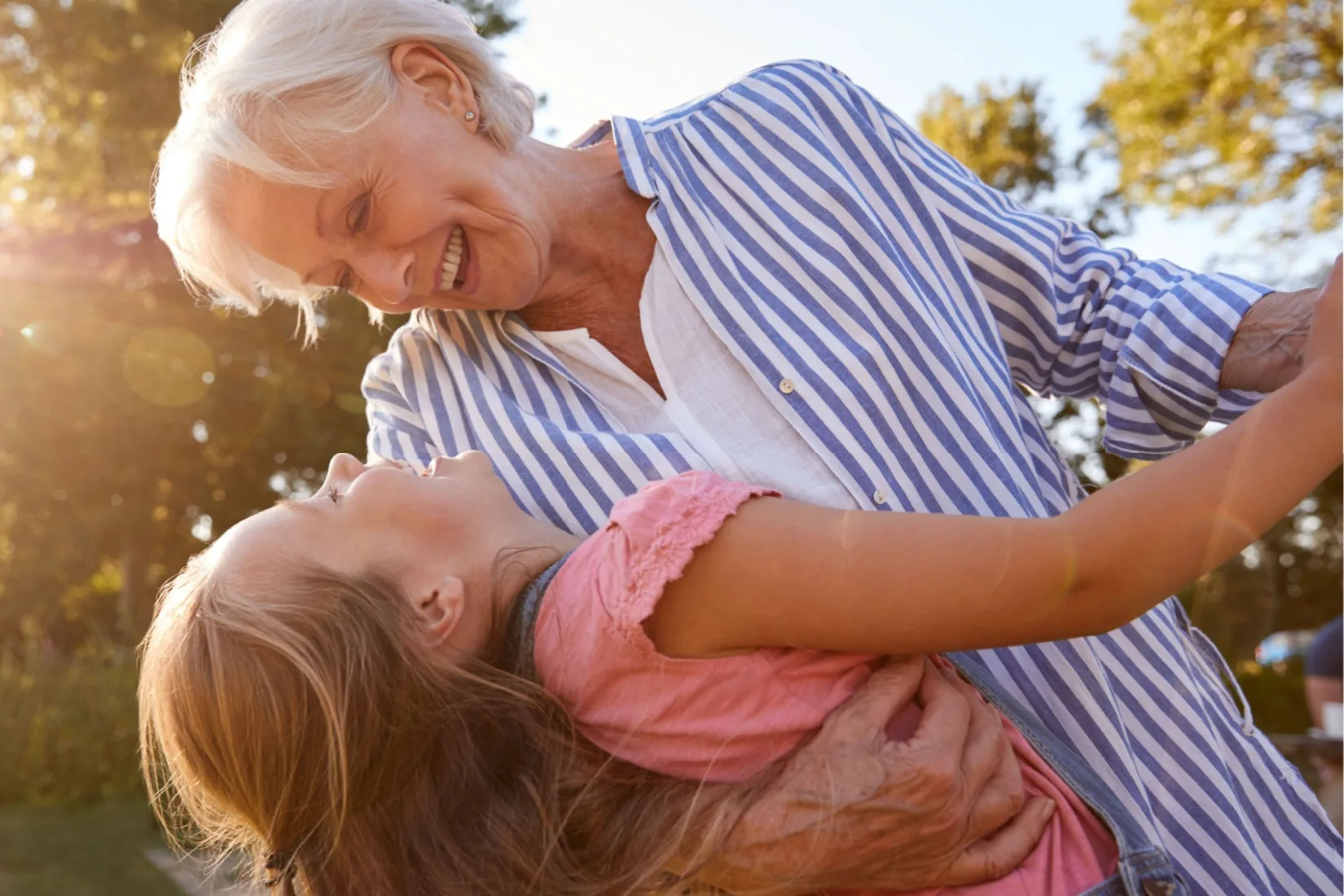A grandmother playing with her granddaughter outside.