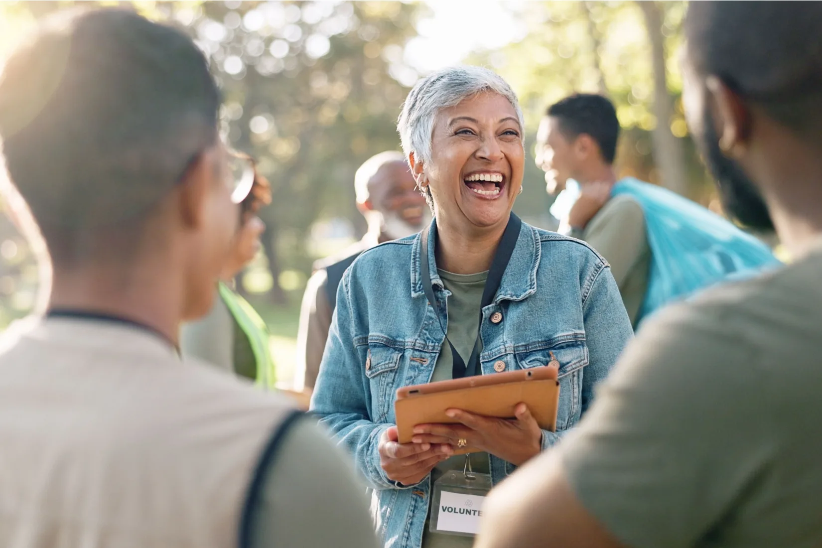 A woman with a clipboard volunteering at an event in a park.