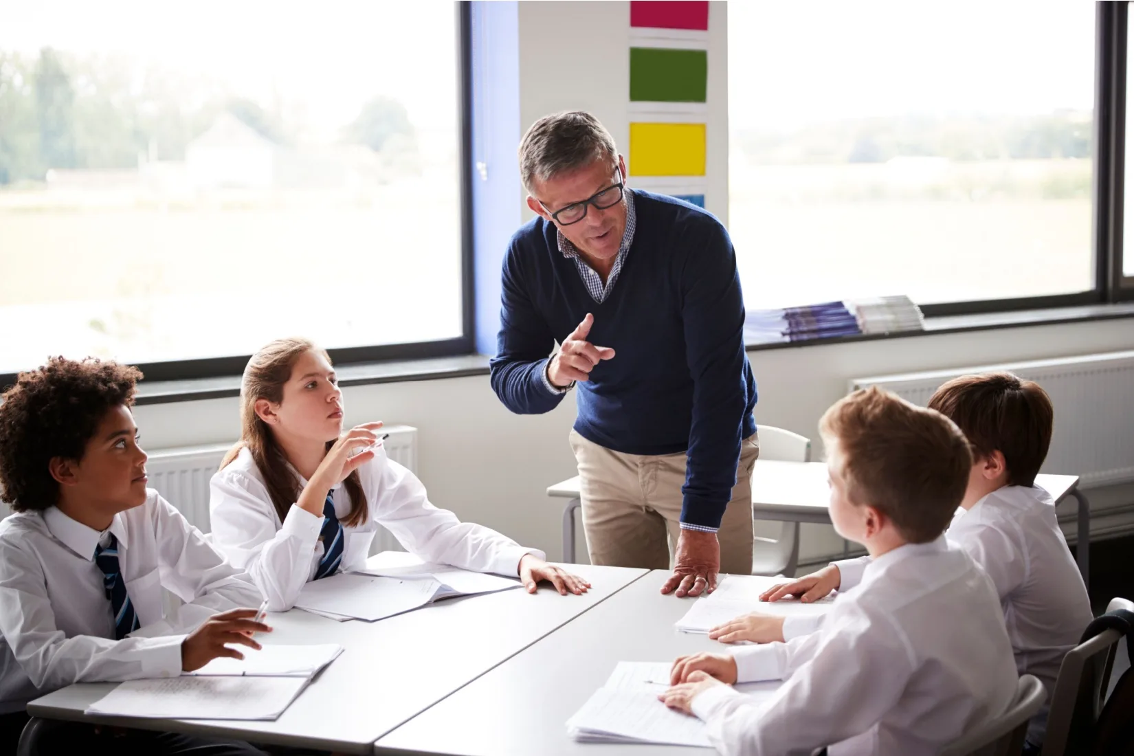 A teacher talking to a group of pupils in a classroom.