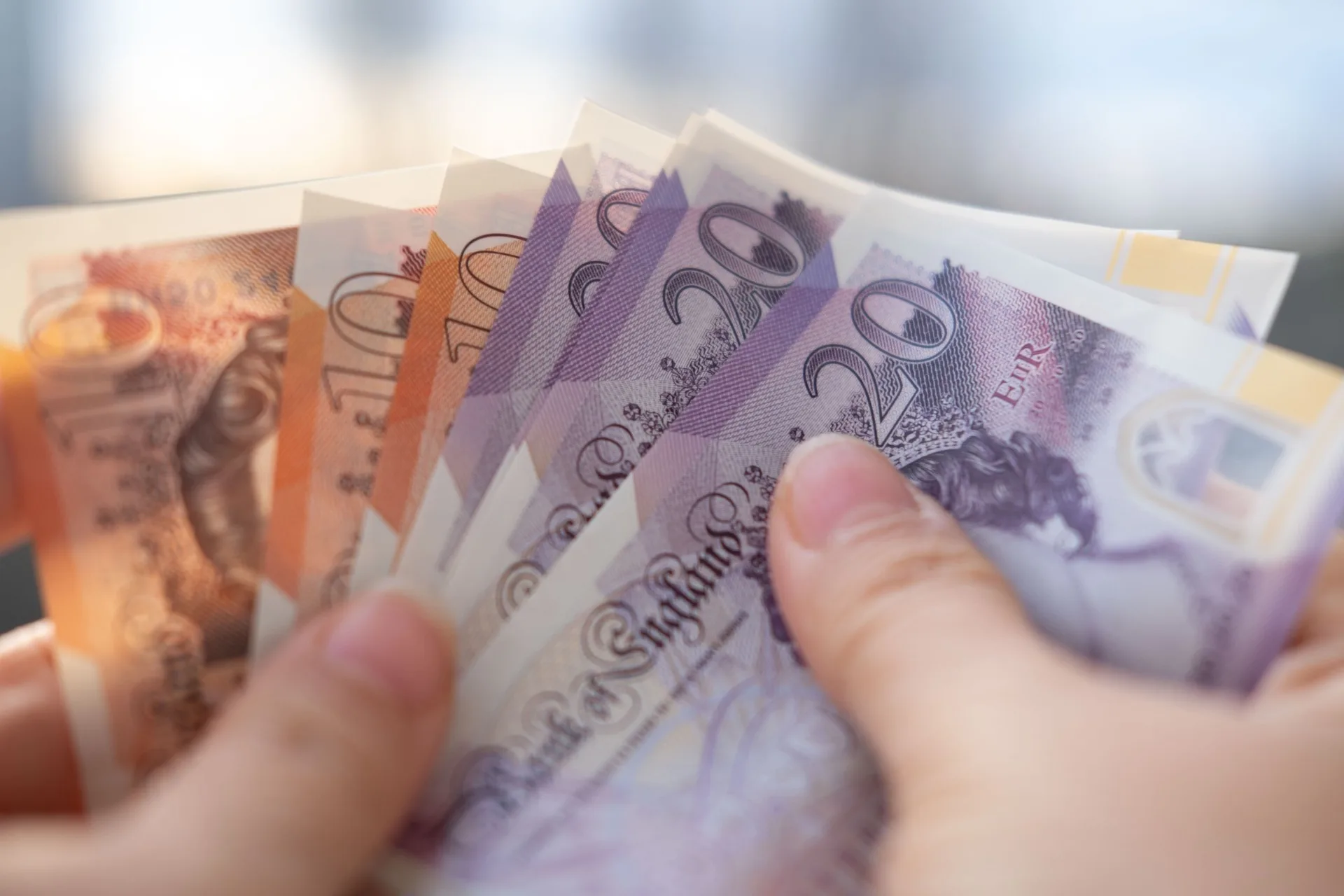 A person holding UK bank notes.
